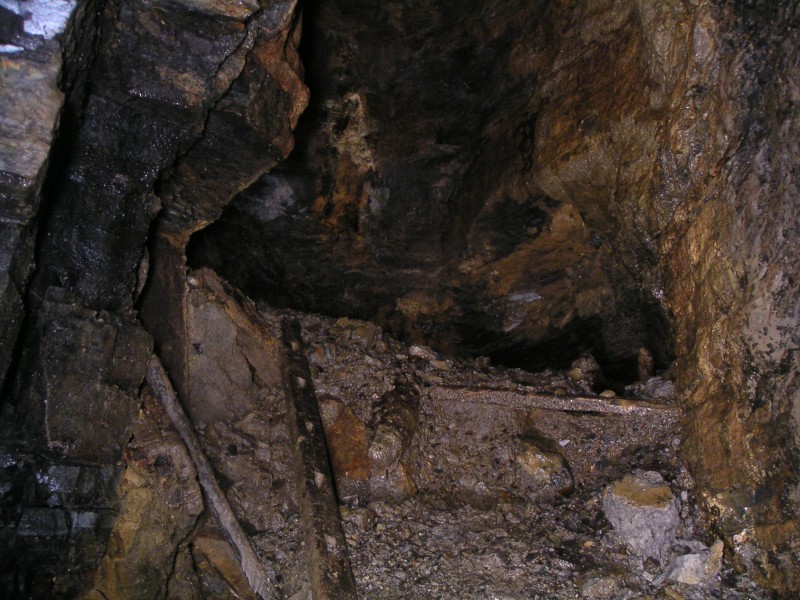 rg_hangingshaw_nw_1stjunc_rise.jpg - If the laddered rise and hopper was a junction then this is the second junction we came to. This is the bottom of a large shaft. Past the debris mound is a flooded level. If we have got our orientation right then this shaft could be the bottom of Charlies Sump. The shaft was wet, but the water coming down it was a very fine mist, strange.